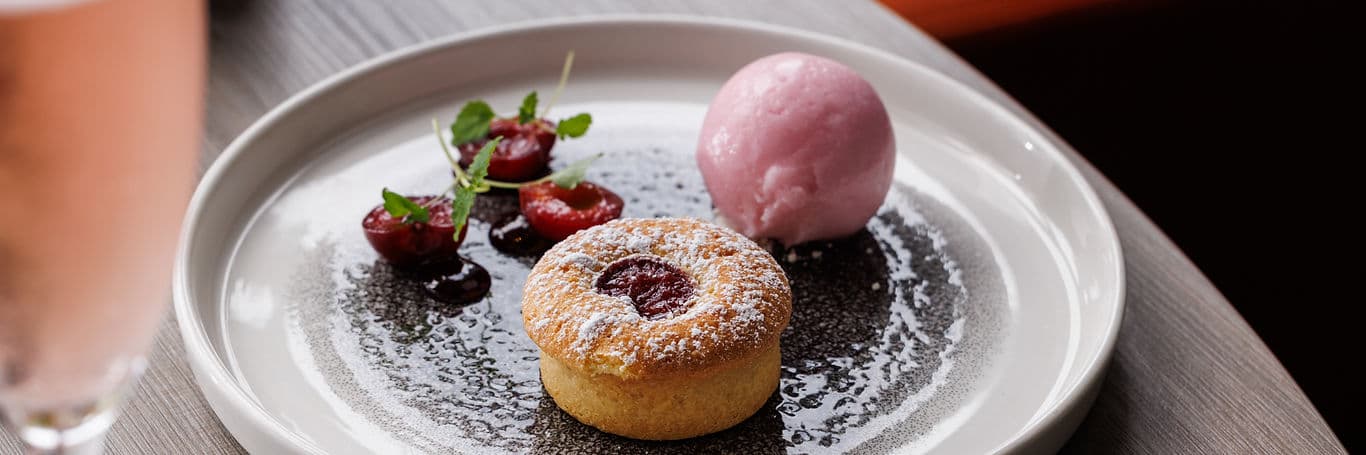Cherry bakewell with raspberry sorbet, dusted with icing sugar, plated at the restaurant.